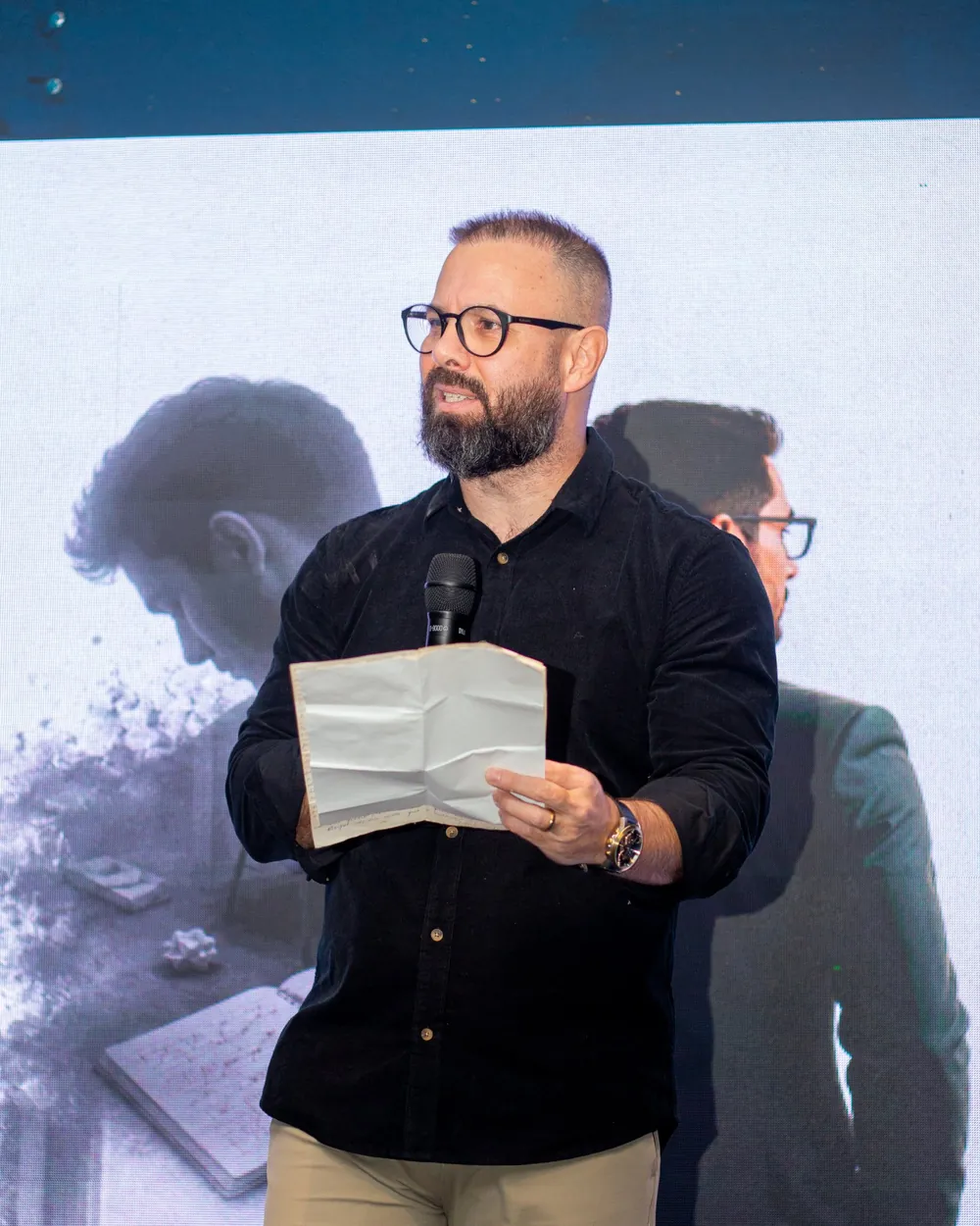 Alexandre Martins lendo uma carta no palco durante uma imersão